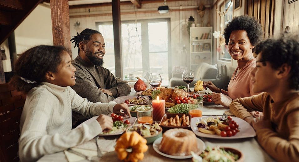 Family of four sitting around table eating a thanksgiving meal