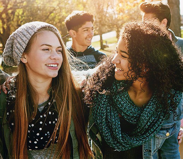 two female teenagers smiling and looking at each other