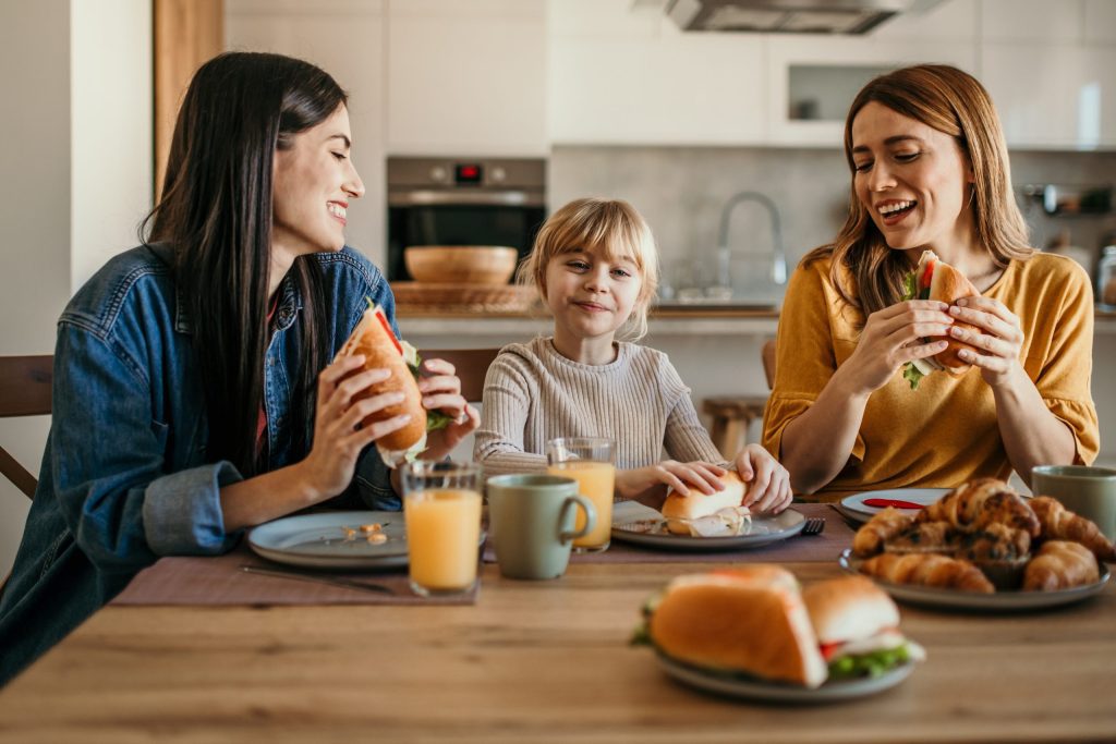 Two women and their adopted girl sharing stories over a breakfast