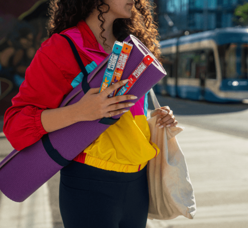 Des femmes tenant des boîtes de Mighty Protein, des sacs et un tapis de yoga